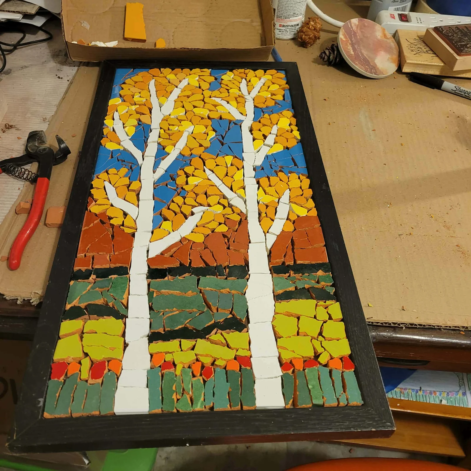 Completed tree mosaic with grout between the colorful tile pieces.